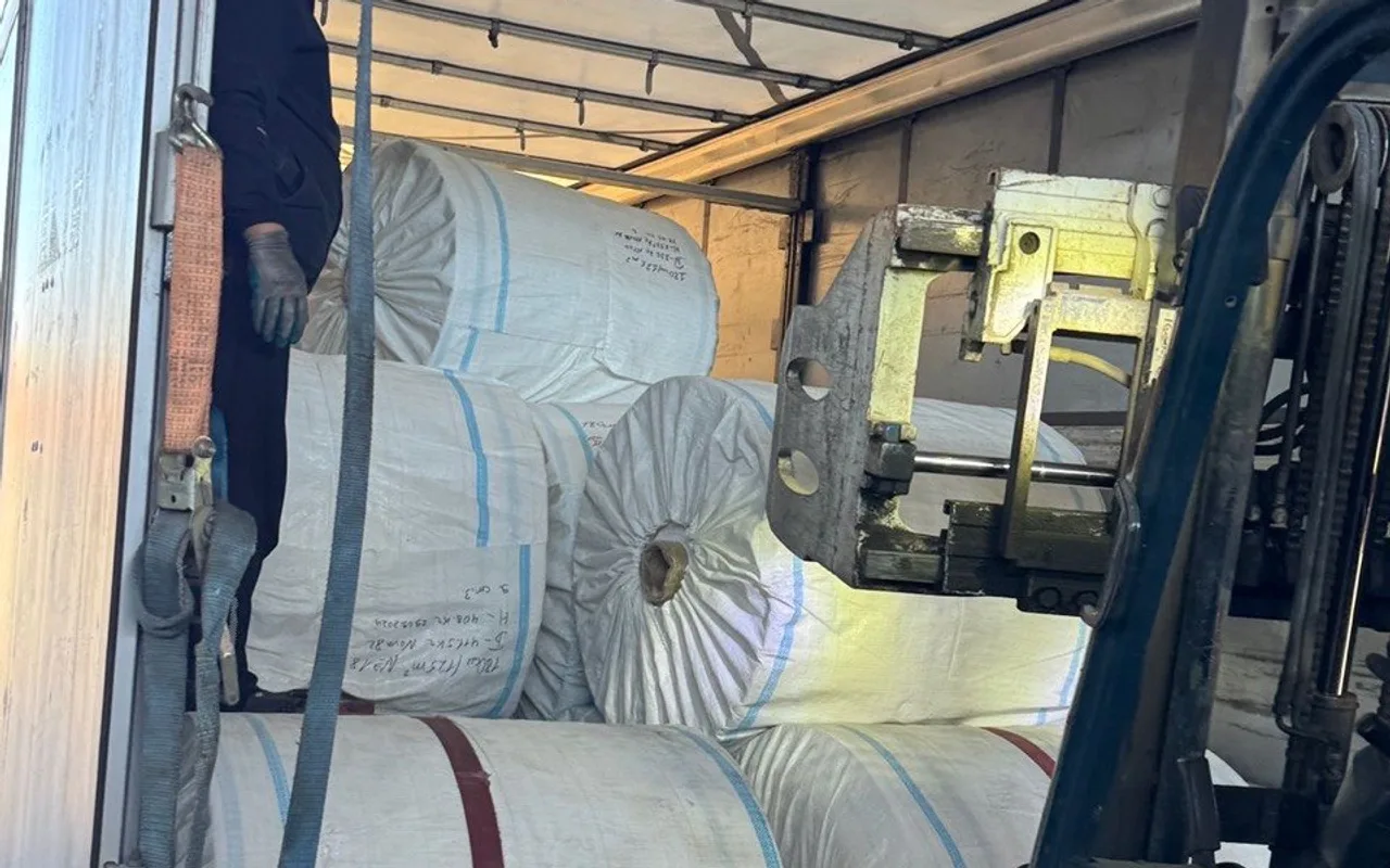 A forklift loading rolls of woven polypropylene web into a truck